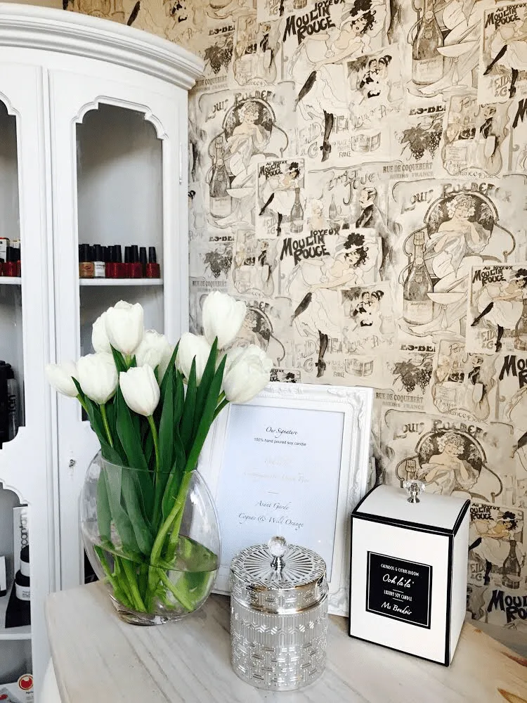 The salon's polish cabinet with white tulips, candles and Moulin Rouge wallpaper