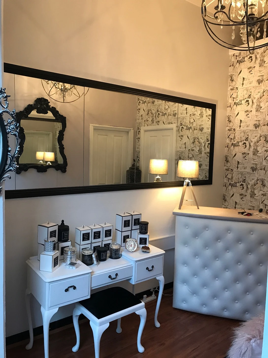 The wide view of the salon — black-framed mirror reflecting panelled doorways, baroque mirror, Queen Anne dressing table with Ms Boudoir candles, chandelier, Moulin Rouge wallpaper