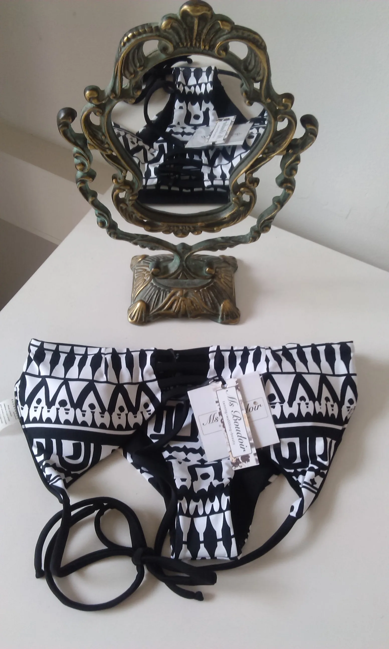 A black-and-white geometric bikini with the Ms Boudoir swing tag — 'tanning · waxxxing · beauty'
